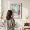 Framed Barcelona Watercolor Wall Art - In Living Room with Woman Looking at it - Portrait