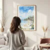 Framed Laguna Beach Watercolor Wall Art - In Living Room with Woman Looking at it - Portrait