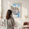 Framed Cinque Terre Manarola Watercolor Wall Art - In Living Room with Woman Looking at it - Portrait