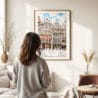 03 - Framed Brussels Watercolor Wall Art - In Living Room with Woman Looking at it - Portrait