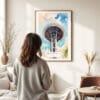 03 - Framed Seattle Space Needle Closeup Watercolor Wall Art - In Living Room with Woman Looking at it - Portrait