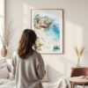 Framed La Jolla Cove Watercolor Wall Art - In Living Room with Woman Looking at it - Portrait