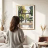 03 - Framed Athens Georgia Arch Watercolor Wall Art - In Living Room with Woman Looking at it - Portrait.jpg