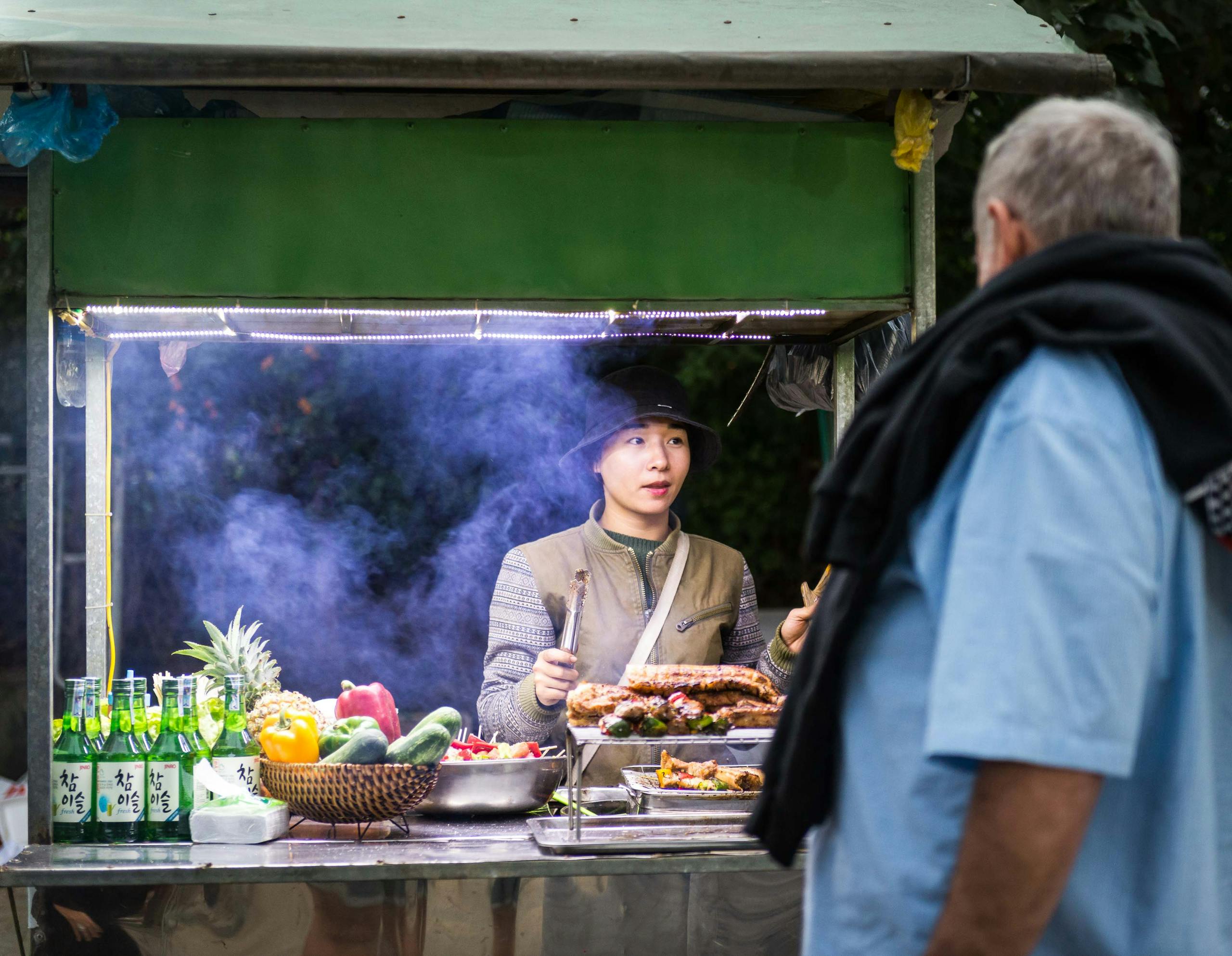 Comprehensive 2-Week Vietnam Travel Itinerary for 2025: North to South Highlights and Planning Tips 6 A street food vendor in Hoi An serves a customer at a bustling food cart.