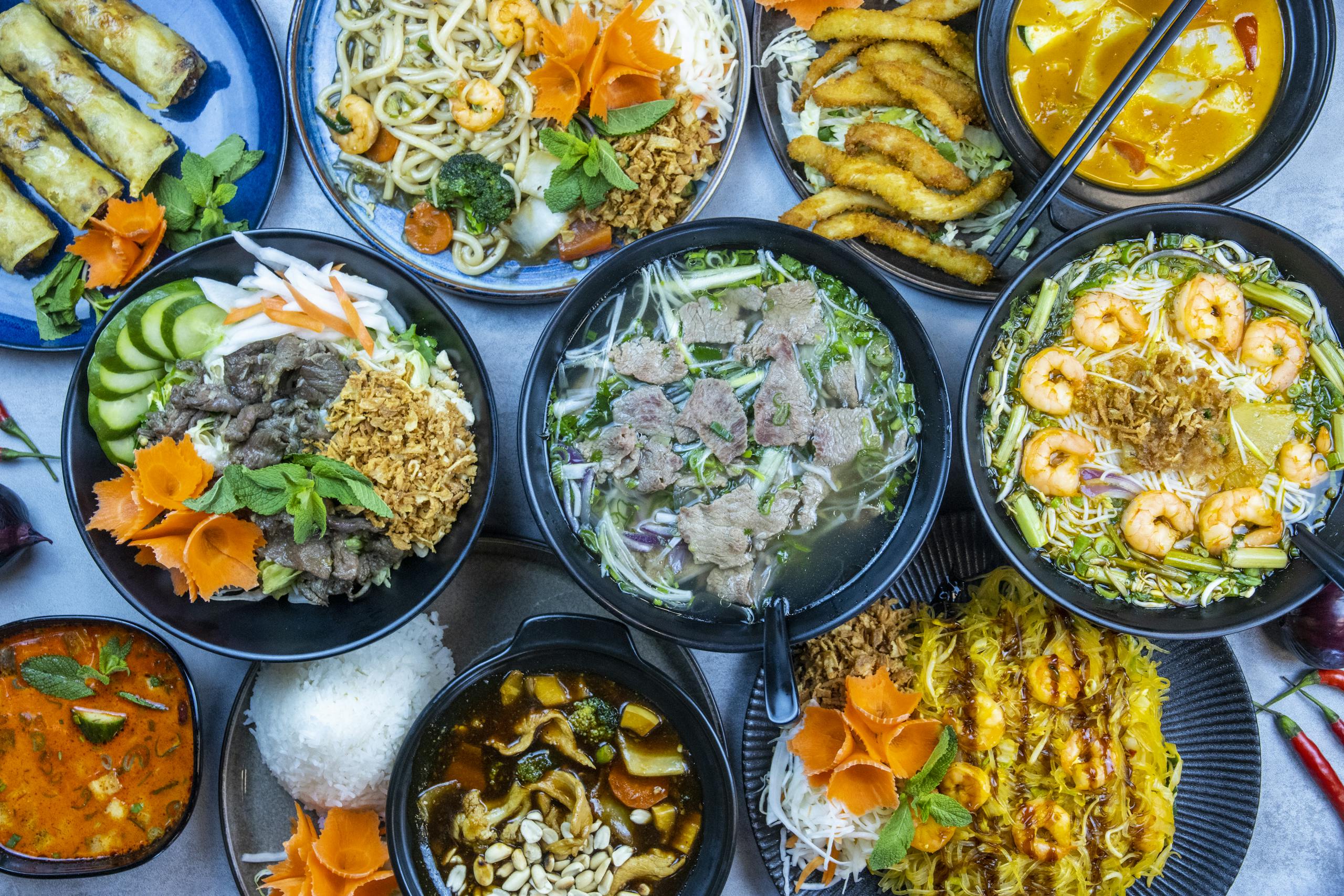 A Culinary Journey Through Vietnam: Discover Authentic Flavors, Street Food, and Dining Culture 1 A vibrant assortment of Asian cuisine, showcasing soups, noodles, and spring rolls, garnished with fresh herbs.