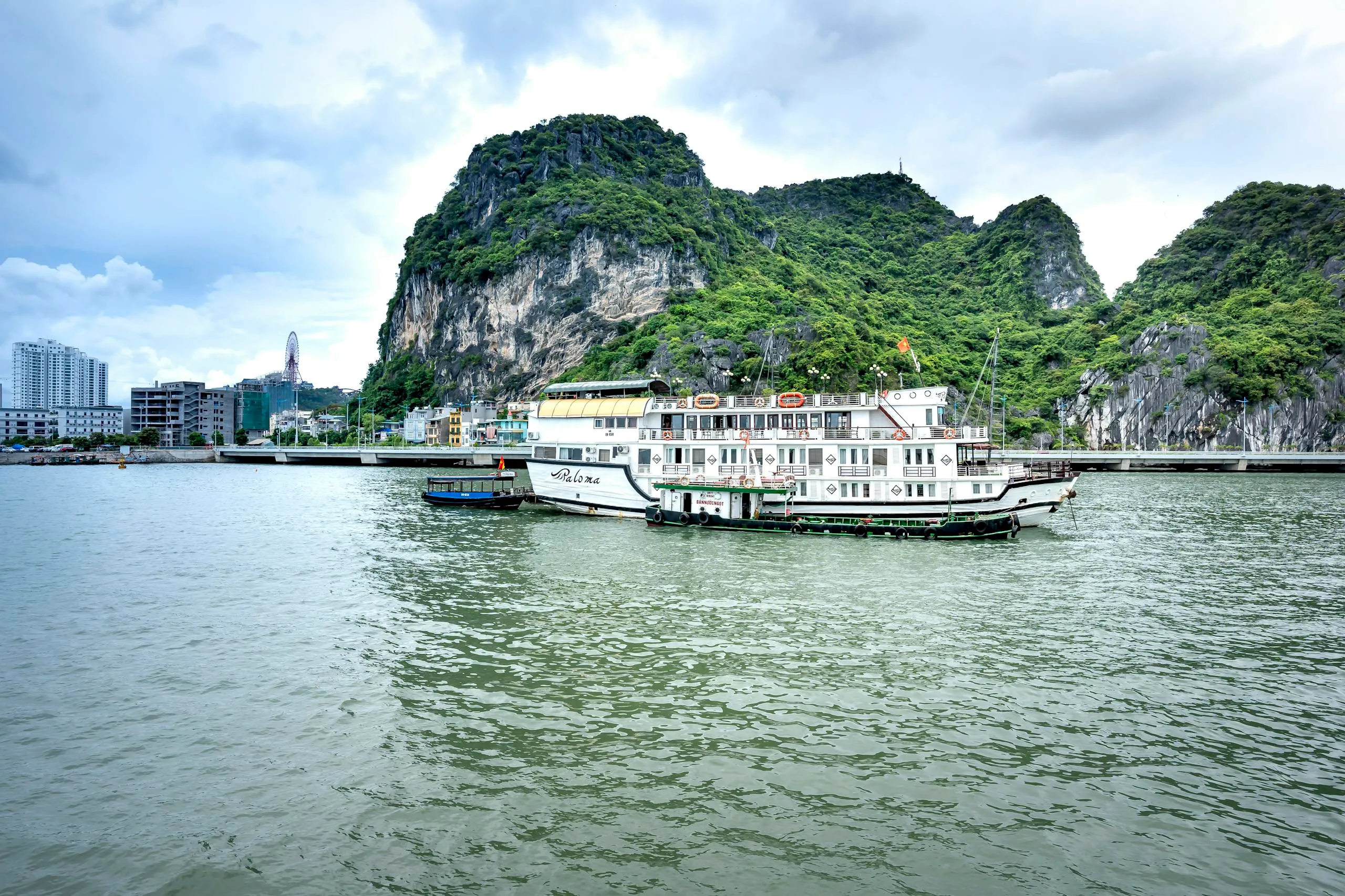 Essential 5-Day Vietnam Itinerary: Explore Vietnam’s Highlights Efficiently 8 Idyllic boats in Halong Bay with limestone cliffs and cityscape backdrop.