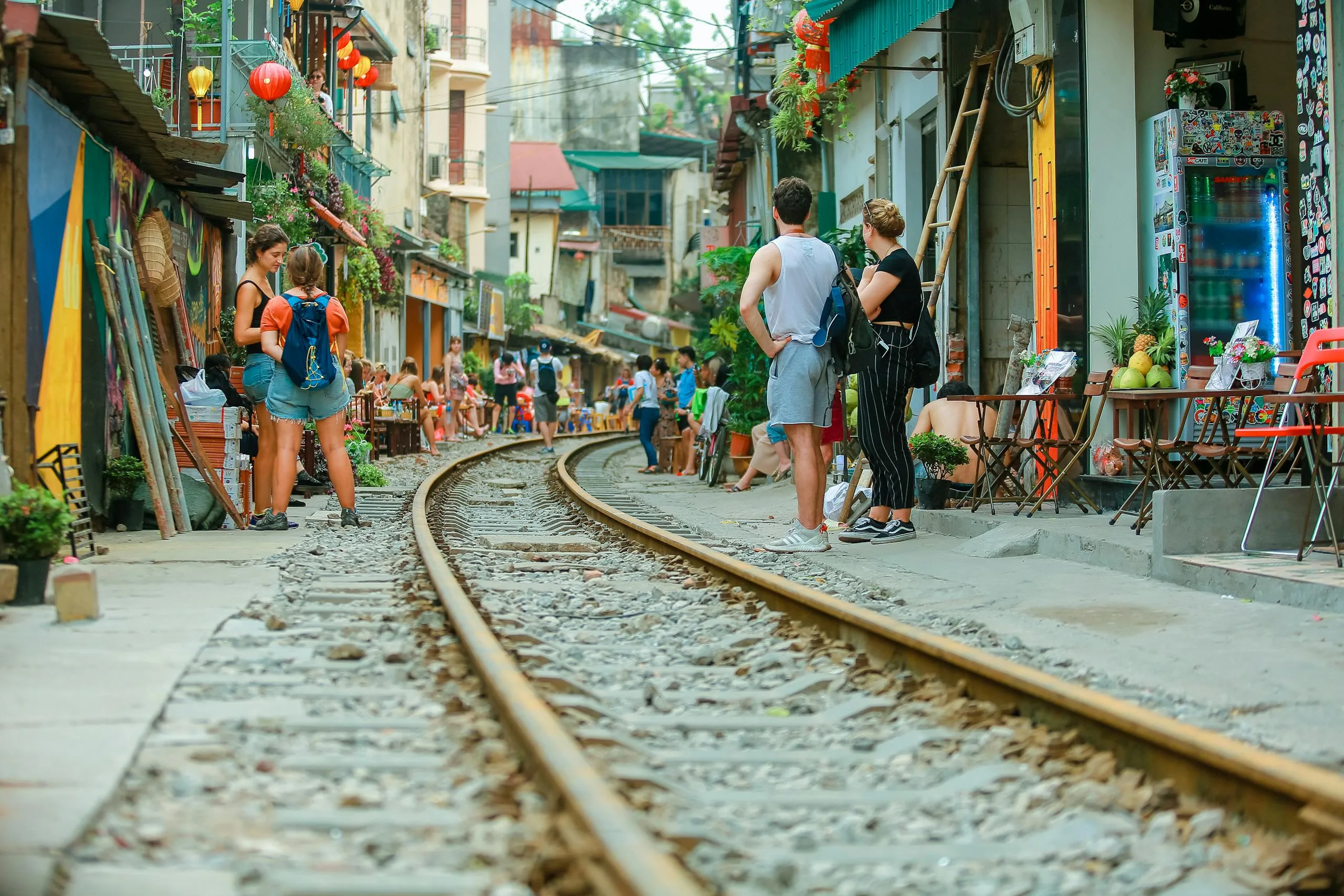Essential 5-Day Vietnam Itinerary: Explore Vietnam’s Highlights Efficiently 5 People relaxing at street cafes alongside railway tracks during daytime.