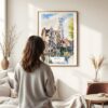 03 - Framed Bruges Belgium Watercolor Wall Art - In Living Room with Woman Looking at it - Portrait.jpg