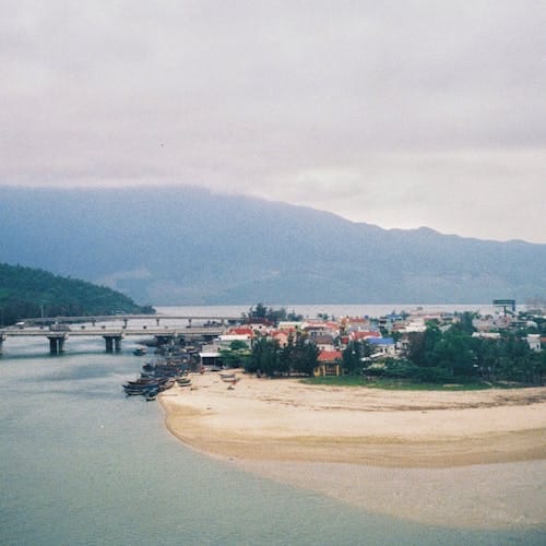 Aerial view of Lang Co Beach and a bridge in Hue, Vietnam. Overcast sky with mountains in the background.