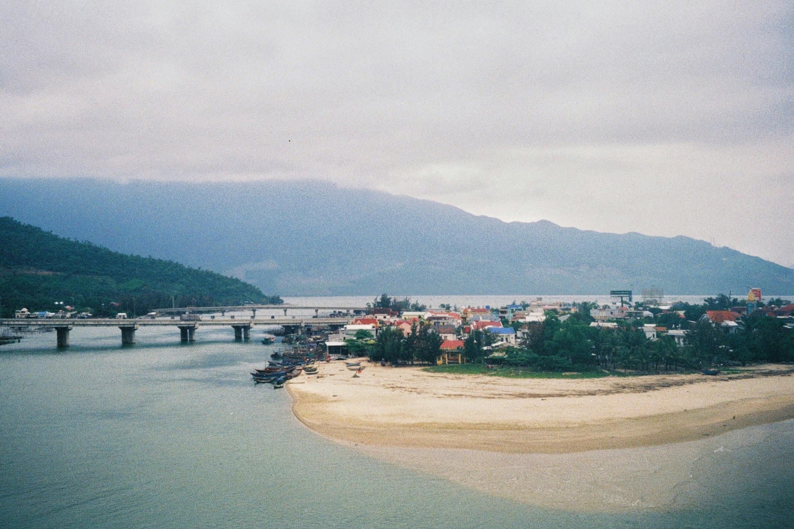 Aerial view of Lang Co Beach and a bridge in Hue, Vietnam. Overcast sky with mountains in the background.