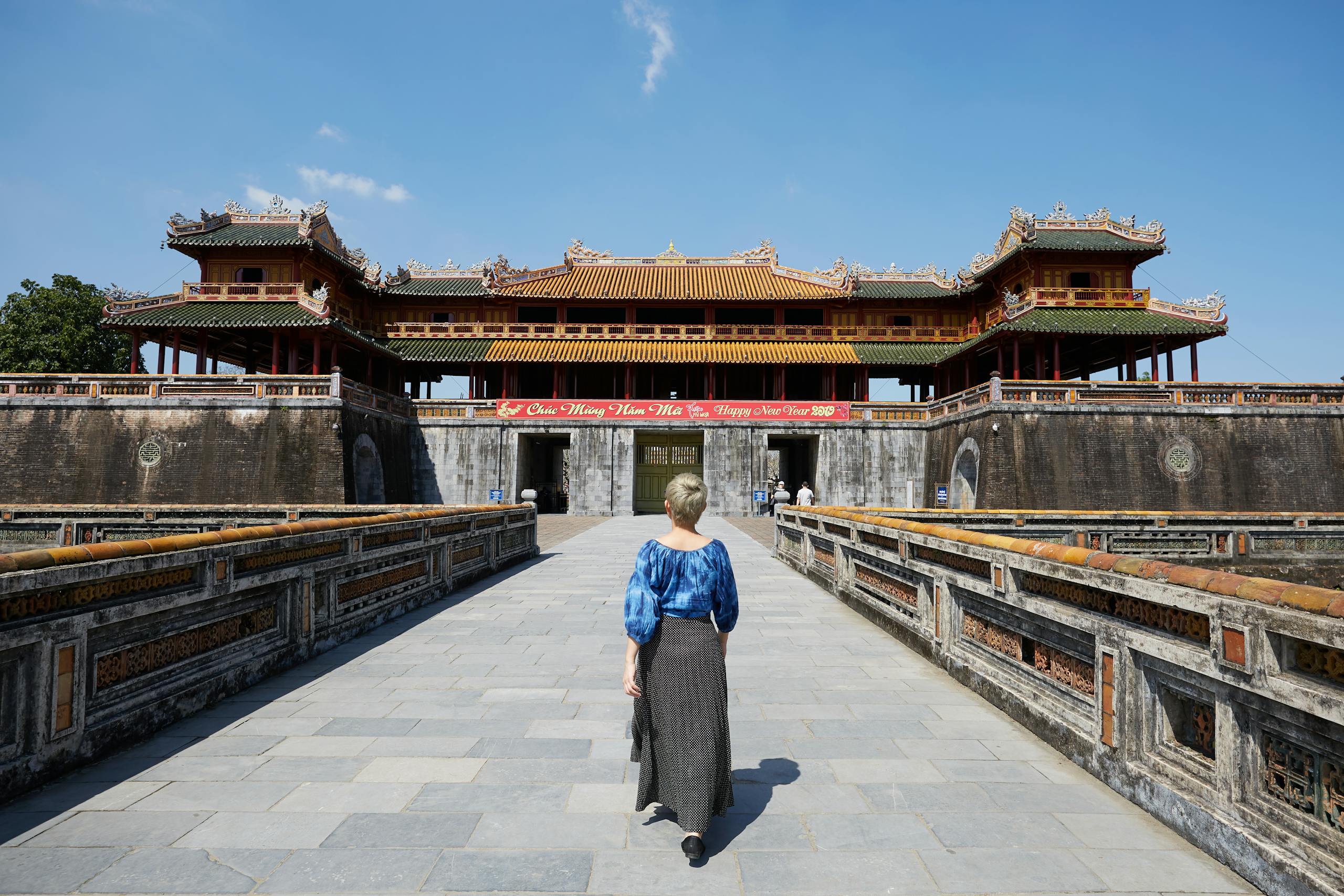 Full body back view of anonymous female traveler strolling on paved walkway near South Gate in Imperial City in Hue