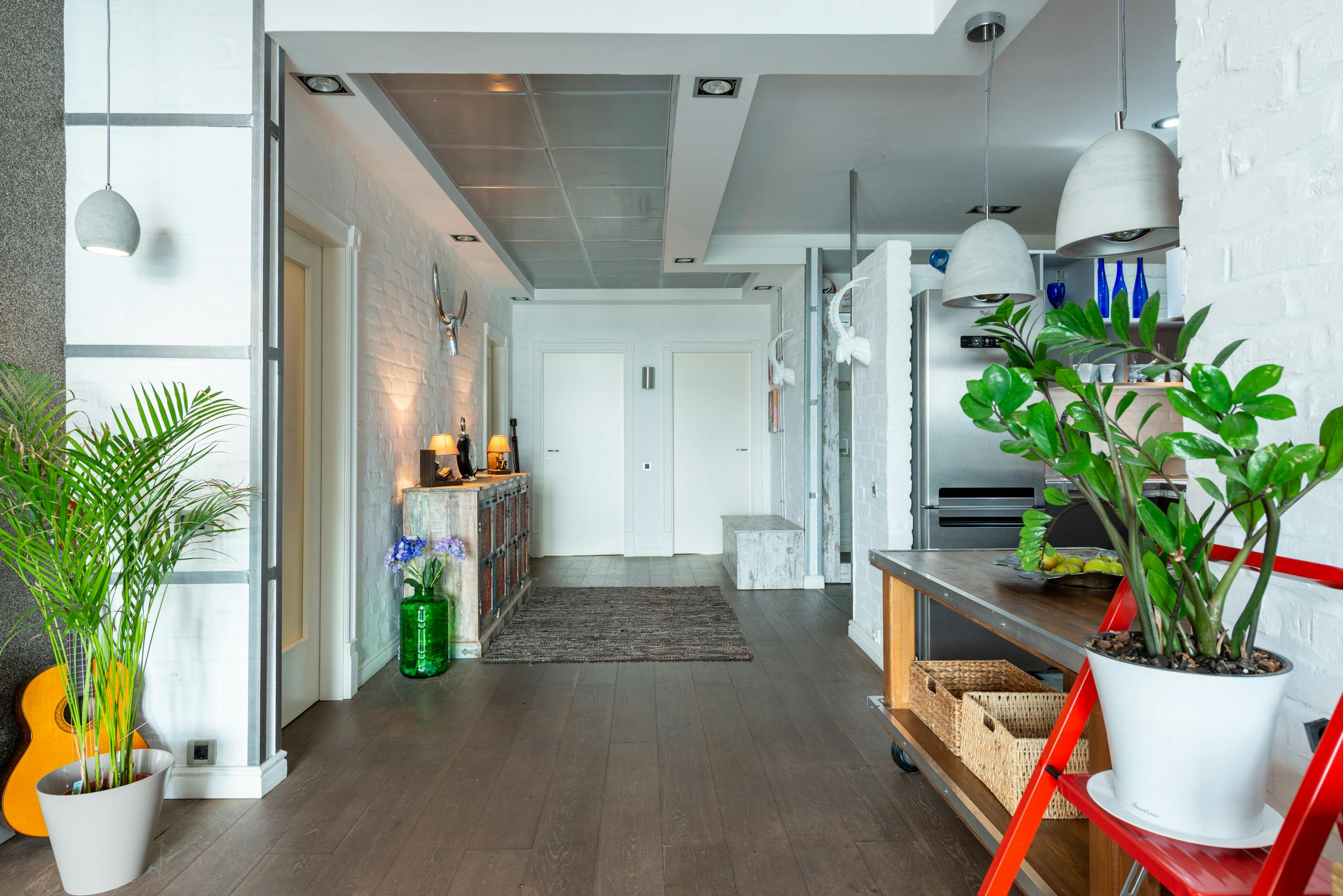 Modern apartment corridor with vibrant decor and plants, highlighting contemporary style.