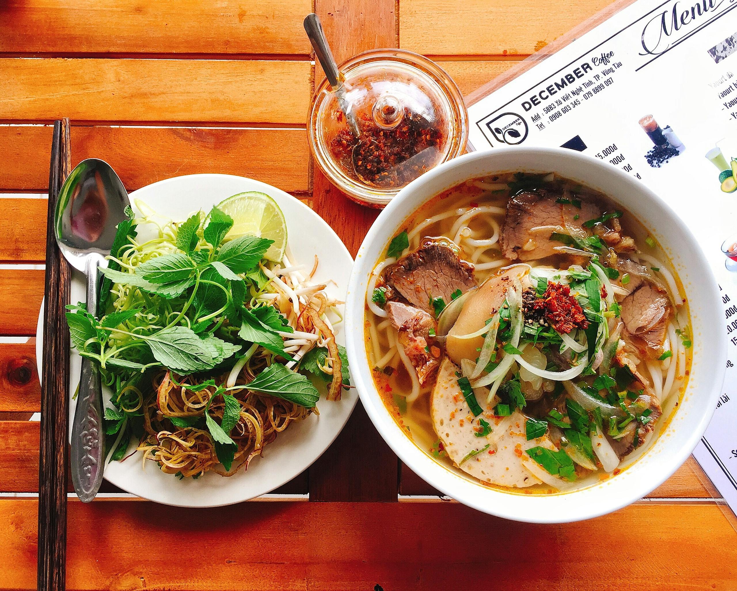 Top Day Trips from Hue: Discover the DMZ, Lang Co Beach & Bach Ma National Park 8 Top view of a delicious noodle soup with fresh herbs, perfect for a hearty meal.