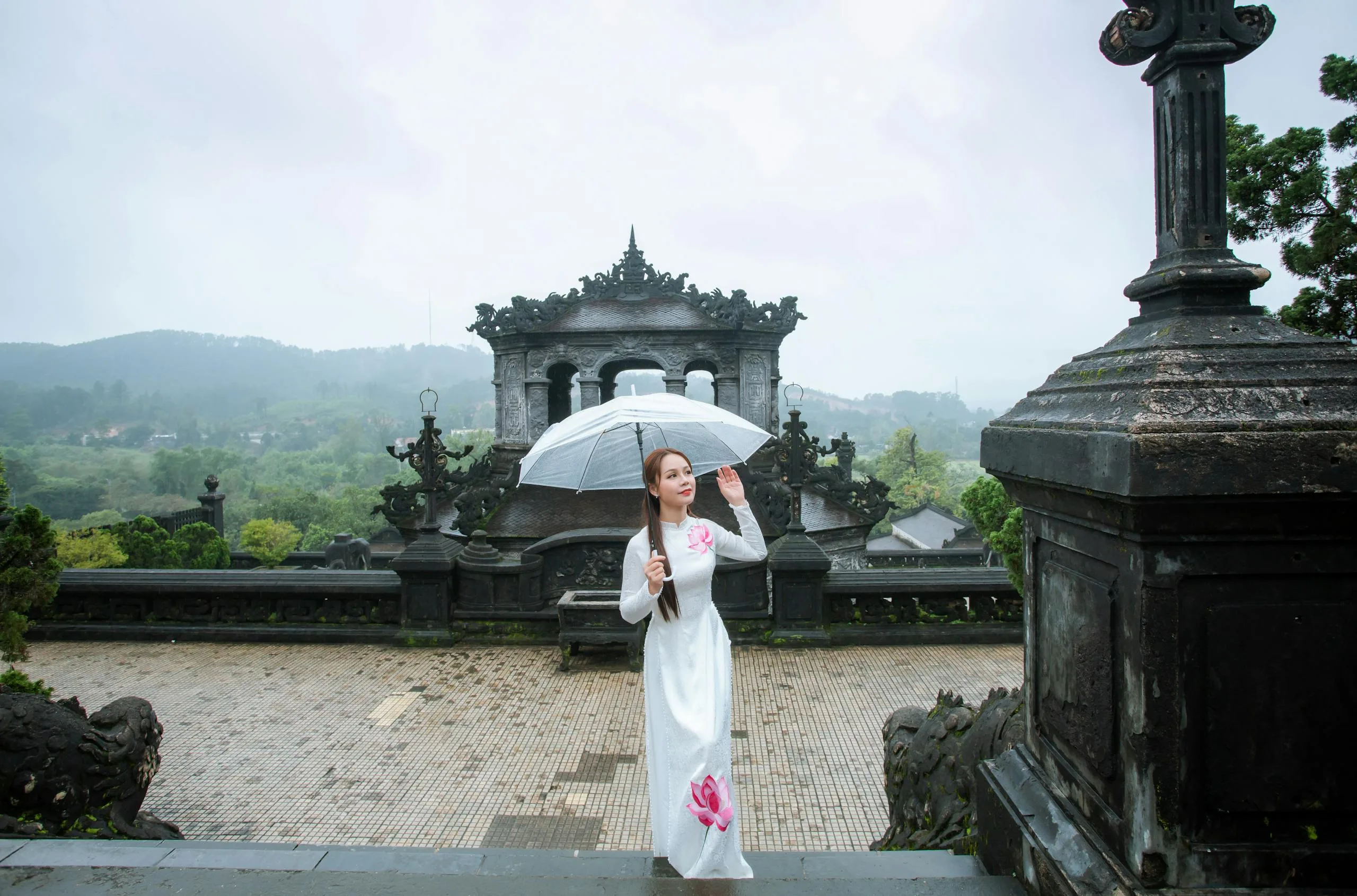 Woman in traditional dress with umbrella at a historical site in Vietnam.