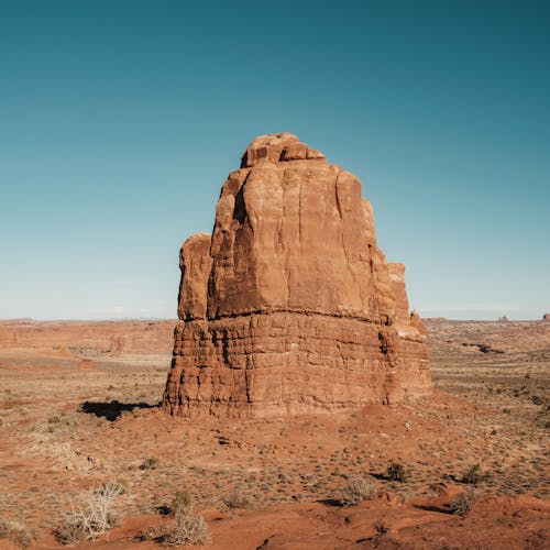 A stunning vertical shot of a rock formation in Arches National Park under a clear blue sky.