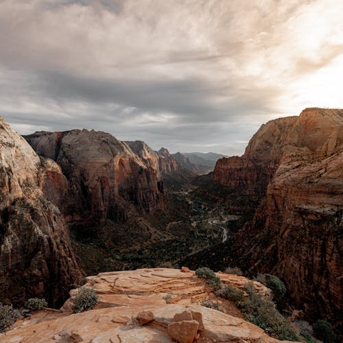 Capture of the dramatic Zion National Park cliffs during a tranquil sunset with a cloudy sky.