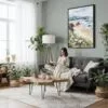 02 - Framed Cannon Beach Oregon Watercolor Canvas Print - Woman reading in Boho Living Room - Vertical.jpg