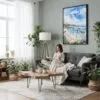 05 - Framed Laguna Beach Coast Watercolor Canvas Print - Woman reading in Boho Living Room - Vertical.jpg