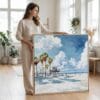 03 - Woman standing in living room with Large Los Angeles Beach Watercolor - Square Canvas Print with Natural floater Frame.jpg