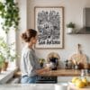 02 - Framed San Antonio City Art - Pencil Style Art Print hanging in Kitchen with woman making coffee - Vertical.jpg