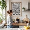 02 - Framed Wichita City Art - Pencil Style Art Print hanging in Kitchen with woman making coffee - Vertical.jpg