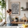 05 - Framed Bangkok City Art - Pencil Style Art Print hanging in Kitchen with woman making coffee - Vertical.jpg